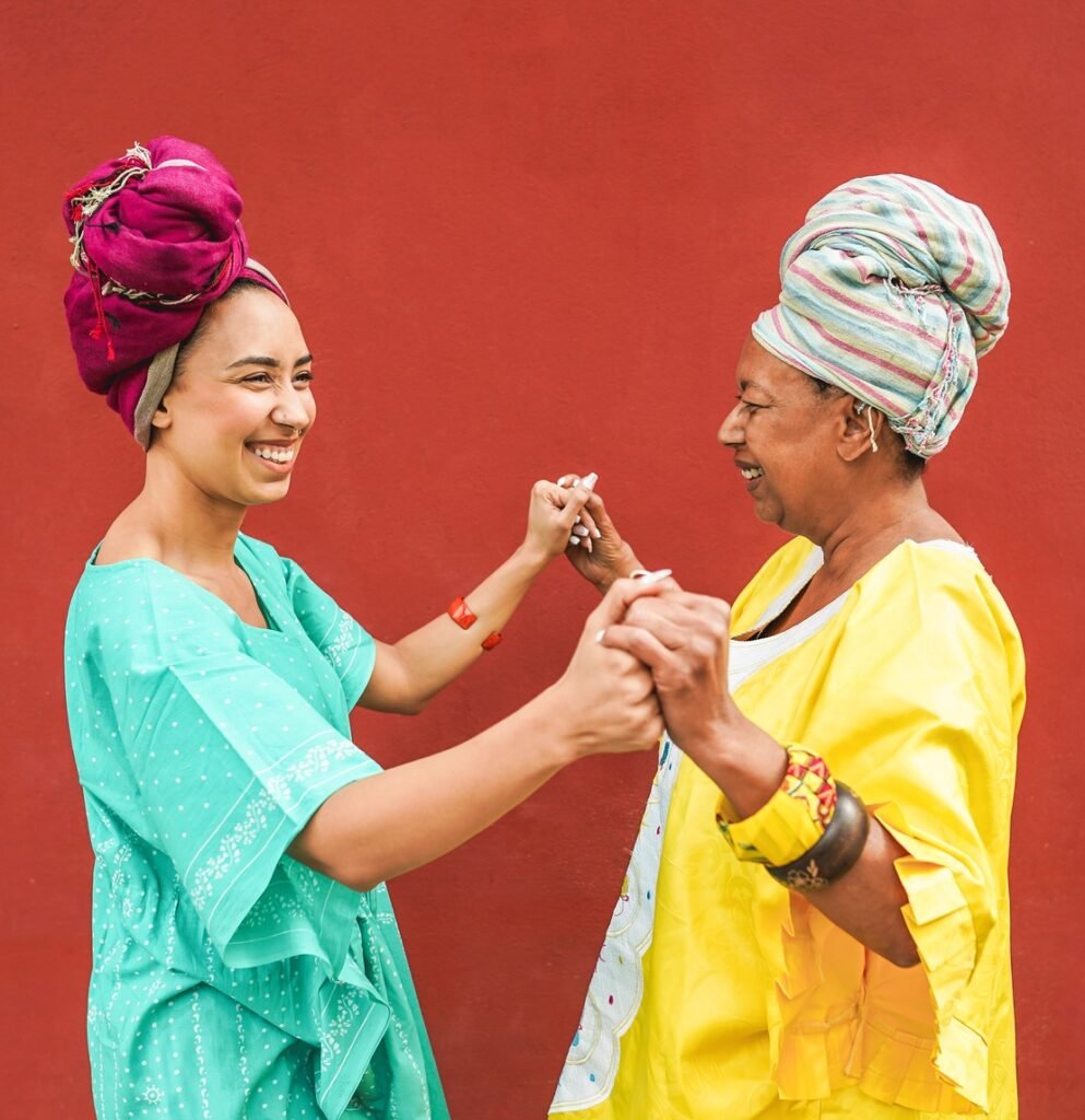 Happy african mother and daughter dancing together while wearing traditional clothes