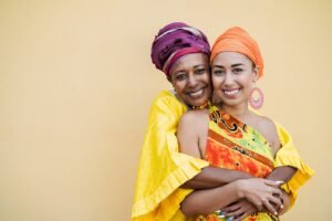 Happy mother and daughter with traditional african dresses smiling on camera